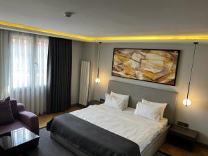 1 dormitorio con 1 cama y una pintura en la pared en The Capital Hotel, en Estambul
