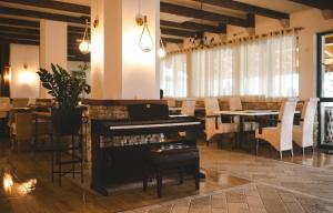 ニクシッチにあるHotel Marshalのピアノ、テーブル、椅子が備わる客室です。