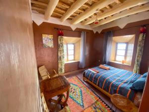 una camera con letto, sedia e finestre di KASBAH ALTAÏR a El Kelaa des Mgouna