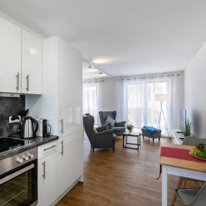 cocina con armarios blancos y sala de estar. en IMMOCITY Apartments Ost en Darmstadt