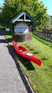 czerwony kajak na trawie obok znaku w obiekcie River Edge Lodges w mieście Perth