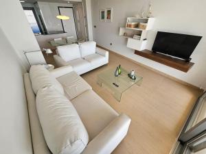 een woonkamer met een witte bank en een tv bij Sidi Luxury 2 (Beach & Golf) in Alicante