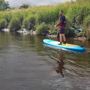 a man standing on a paddle board in the water at River Edge Lodges in Perth