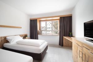 a hotel room with two beds and a flat screen tv at Snooze Apartments in Holzkirchen