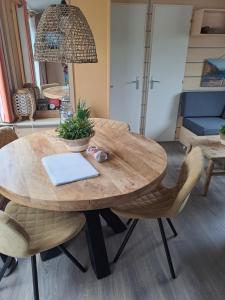 una mesa de madera con sillas y un ordenador portátil. en Vakantie bij 17, en Serooskerke