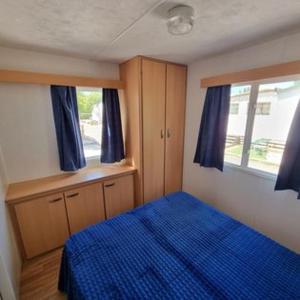 een slaapkamer met een blauw bed en een raam bij MOBILE HOME COSY 4/5 personnes in Hyères