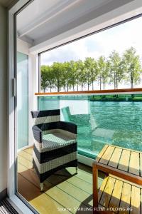 uma varanda com uma cadeira, uma mesa e uma janela em KD Hotelship Düsseldorf Comfort Plus em Dusseldorf