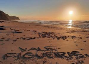 un cartel escrito en la arena en una playa en Coureladaltura, en Aljezur