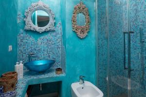 een blauwe badkamer met een wastafel en een spiegel bij Casa delle Mimose by Wonderful Italy in Badesi