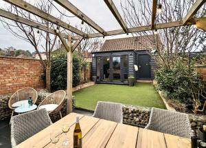 eine Terrasse mit einem Tisch und Stühlen sowie einem Garten in der Unterkunft Happy Place, Sheringham Stunner - Crabpot Cottages Sheringham in Sheringham