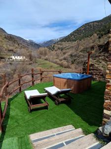 a backyard with a hot tub and two lounge chairs at Casa Rural Cortijo Molino Altero in Trevélez