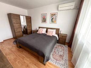 a bedroom with a large bed with pink pillows at Апартамент за гости Бажолета - светъл и уютен дом в сърцето на Ямбол in Yambol