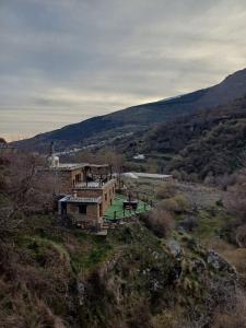 una casa en la cima de una colina en un campo en Casa Rural Cortijo Molino Altero, en Trevélez