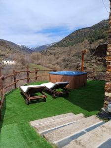 une cour avec un bain à remous et des chaises sur la pelouse dans l'établissement Casa Rural Cortijo Molino Altero, à Trevélez