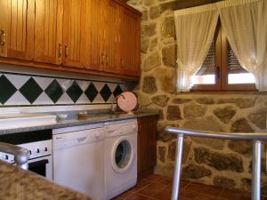 Peñalba de ÁvilaにあるCasa rural a escasa distancia de Ávila by Alterhomeの石壁のキッチン(洗濯機付)