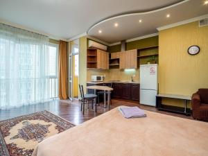 Il dispose d'une cuisine et d'un salon avec une table et un réfrigérateur. dans l'établissement Однокомнатная квартира-студия, à Almaty