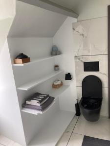 a bathroom with a black toilet and white walls at Bobs Bnb in Bruges