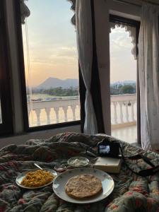 three plates of pizza on a bed with a window at Devi Villa in Udaipur