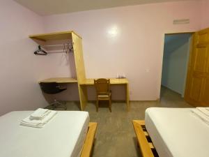 Cette chambre comprend deux lits, un bureau et une table. dans l'établissement Spencer Residencial APARTAMENTOS, à Praia