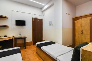 コルカタにあるOYO Hotel Dinarのベッド1台とテレビが備わる小さな客室です。