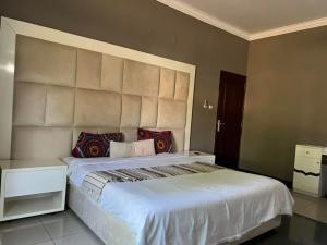 ein Schlafzimmer mit einem großen weißen Bett mit roten Kissen in der Unterkunft MATOLA AcCOMMODATION in Matola