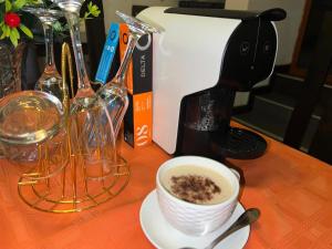 MATOLA AcCOMMODATION في Matola: كوب من القهوة على طاولة بجوار آلة صنع القهوة