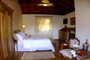 a bedroom with a white bed and a window at Lis Bleu Pousada in Tiradentes