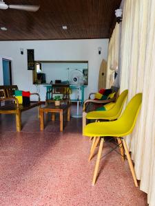 a living room with yellow chairs and a table at Ceylon Glory Hostel in Negombo