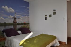 a bedroom with a bed with a painting of a windmill at chambres d'hôtes du clos du roi in Pontorson