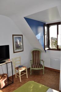 ein Wohnzimmer mit 2 Stühlen und einem TV in der Unterkunft chambres d'hôtes du clos du roi in Pontorson
