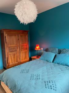 a bedroom with a large bed with a blue wall at Maison Valette in Roussillon-en-Morvan