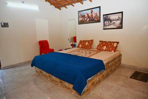 a bedroom with a bed and a red chair at Dwarkesh Farm&Resort in Somnath