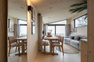 een eetkamer en een woonkamer met een tafel en stoelen bij Hello Zeeland - Tiny House Zeeuwse Liefde 11 in Westkapelle