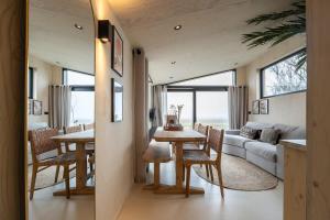 ein Esszimmer und ein Wohnzimmer mit einem Tisch und Stühlen in der Unterkunft Hello Zeeland - Tiny House Zeeuwse Liefde 11 in Westkapelle