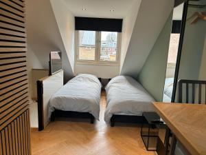 two beds in a small room with a window at Bnb de leeuw in Badhoevedorp