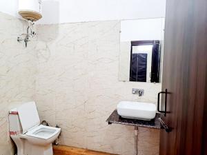 a bathroom with a white sink and a toilet at Hotel Maharaja - Majnu-ka-tilla in New Delhi