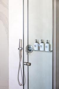 una porta doccia con quattro articoli da toeletta su una mensola di Nammos Hotel Mykonos a Psarou