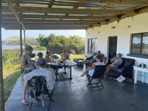 un grupo de personas sentadas en sillas en un patio en Cheerful 10 sleeper cottage - Shower with a view. en Lusikisiki