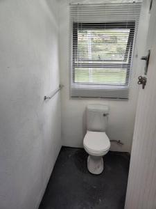 baño con aseo blanco en una habitación en Cheerful 10 sleeper cottage - Shower with a view., en Lusikisiki