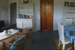 sala de estar con mesa y sillas y cocina en Cheerful 10 sleeper cottage - Shower with a view., en Lusikisiki