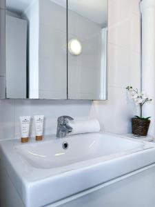 La salle de bains est pourvue d'un lavabo blanc et d'un miroir. dans l'établissement 841 - Panthéon chic in Paris Olympic Games 2024, à Paris