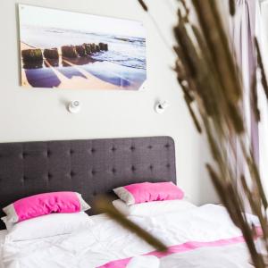 a bedroom with a bed with pink pillows and a headboard at Apartamenty Za Regą in Mrzeżyno