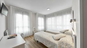 ein Hotelzimmer mit zwei Betten und einem Schreibtisch in der Unterkunft Hotel Rico in Luarca + 17 Fotos