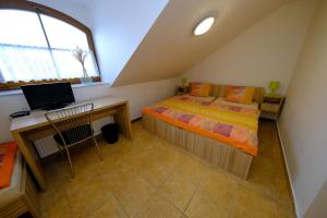 a bedroom with a bed and a desk with a computer at Penzion Farma in Lednice