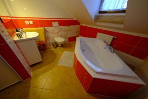 Baño rojo con bañera y lavamanos en Penzion Farma, en Lednice