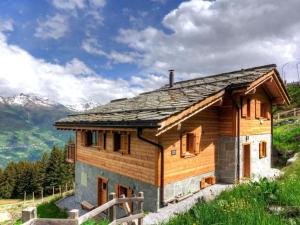 a wooden house on a hill with mountains in the background at Chalet Bryher in Les Collons