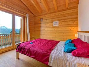 Cama en habitación de madera con ventana grande en Chalet Bryher en Les Collons