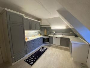 uma cozinha no sótão com armários azuis e um tapete em Holiday apartment Möwennest em Lindholm