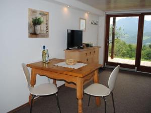 a room with a wooden table and chairs and a television at Holiday apartment on the slope in Berchtesgaden