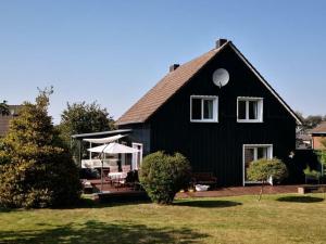 een zwart huis met een veranda en een gazon bij Holiday home Eifel H time out in Monschau